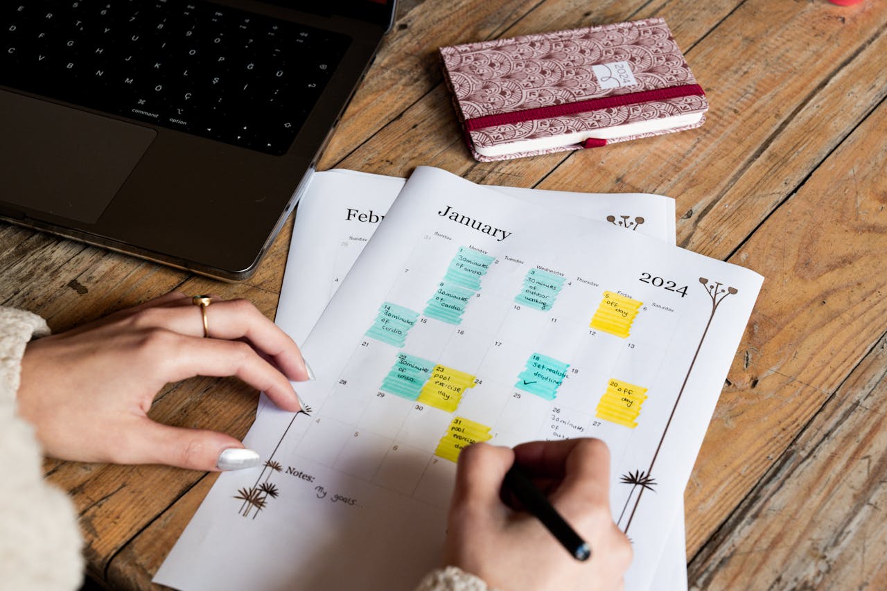 Hands checking and marking events on a 2024 calendar. Organized workspace theme.