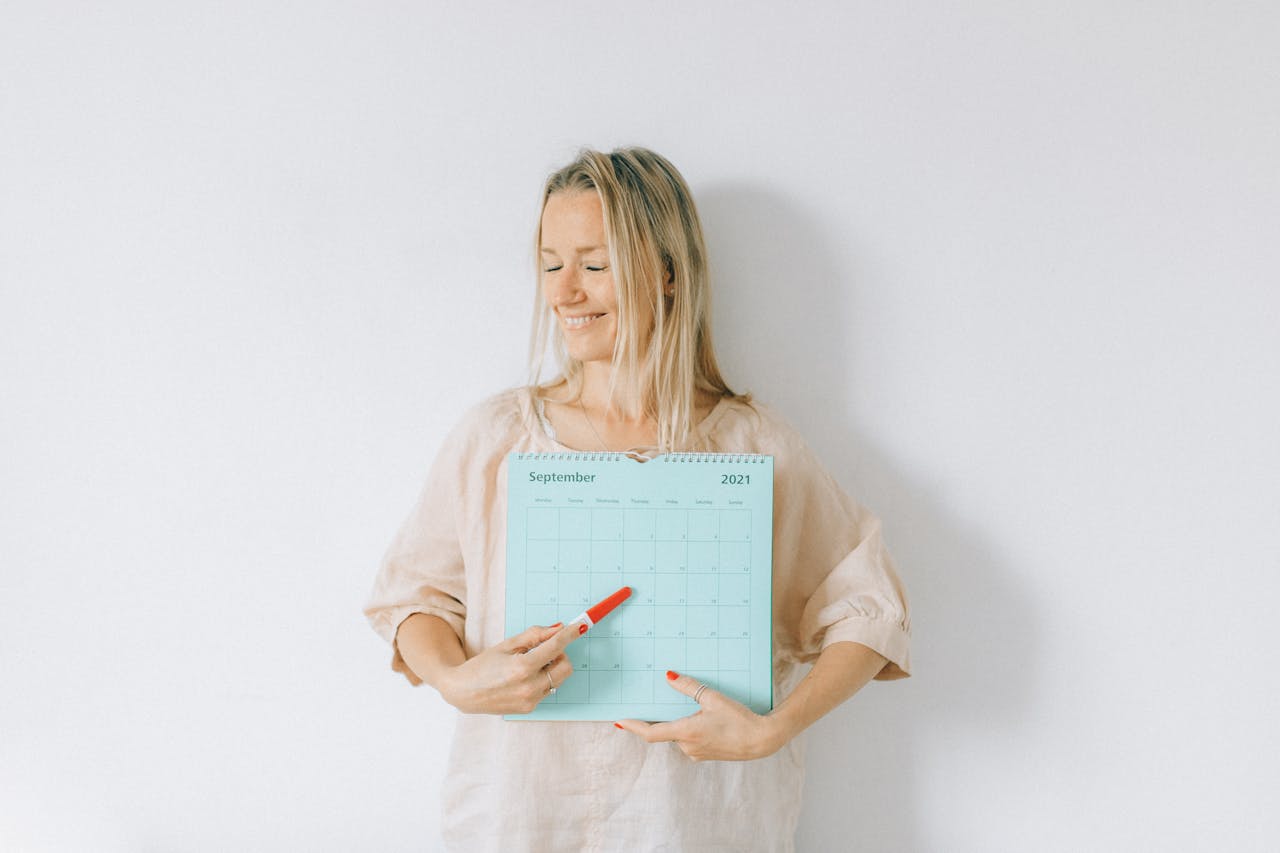 Smiling woman points at a date on a calendar, conveying excitement and anticipation.